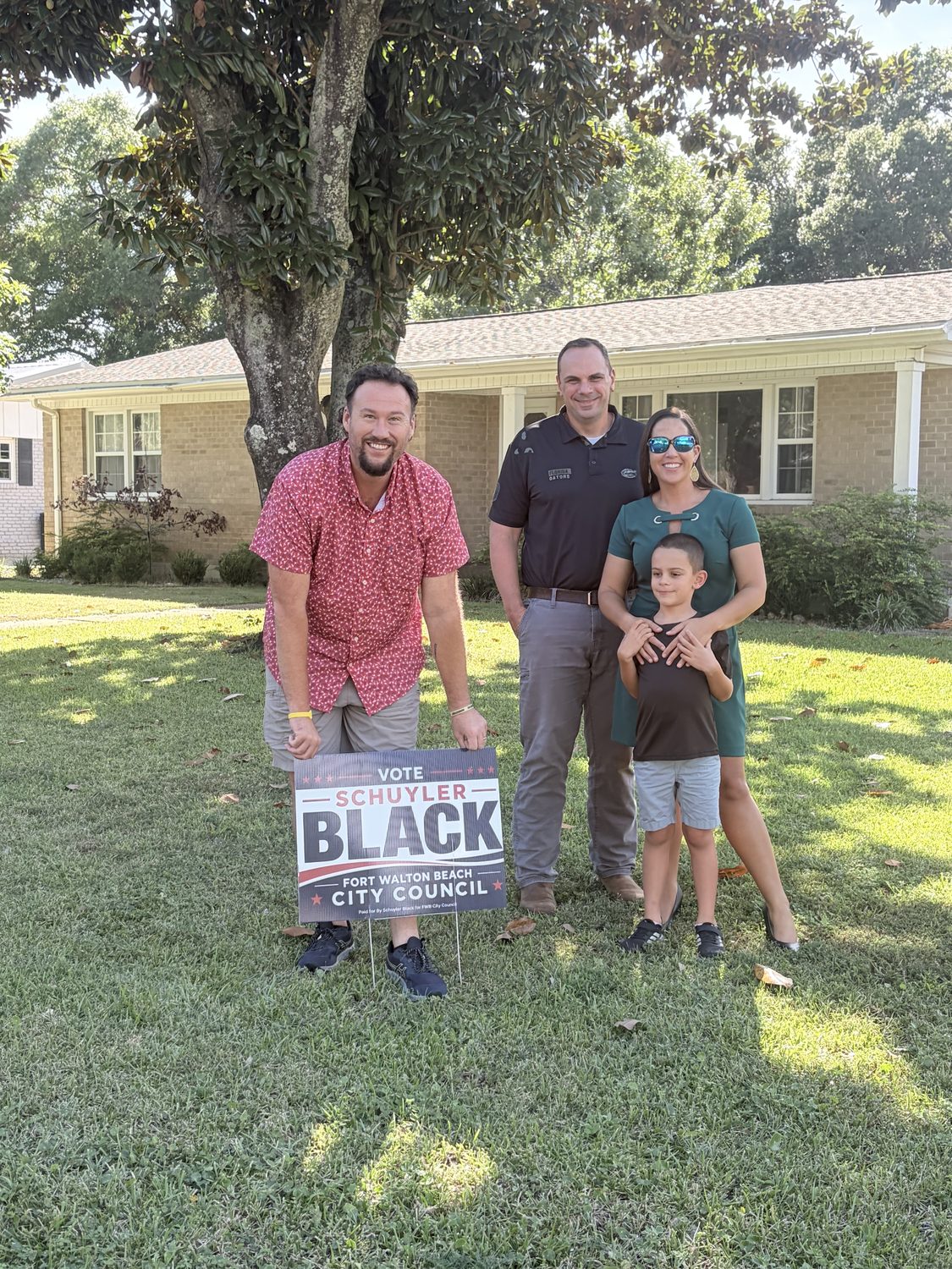 Schuyler Black placing a campaign yard sign in the front yard of a Fort Walton Beach family who is supporting him.